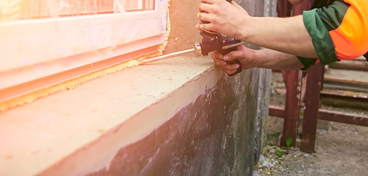 A construction worker sticks sealing foam tape on a window in a house. Window frame replacement.