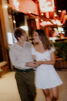 A couple happily enjoying a romantic and intimate walk together at night, dressed in stylish casual clothing