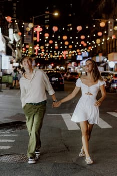 A charming couple leisurely strolls through a bustling city street, which is beautifully adorned with vibrant lanterns