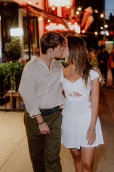 A couple happily enjoying a romantic and intimate walk together at night, dressed in stylish casual clothing