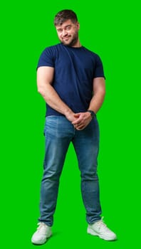 Man standing with a thoughtful expression in a casual outfit against a green background in studio