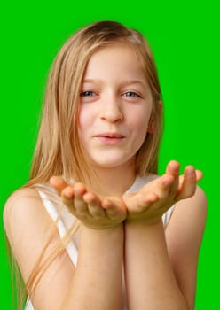 A young girl playfully blowing a kiss against a vibrant green background in studio