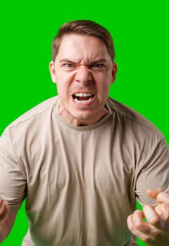 Man expressing intense frustration while standing against a bright green background in studio