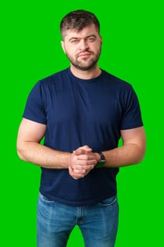 Man standing with a thoughtful expression in a casual outfit against a green background in studio