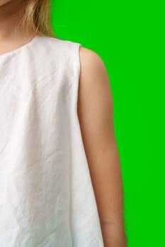 A child stands in front of a bright green background close up photo