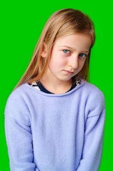 A young child in a light purple sweater gazes against a vibrant green background while deep in thought