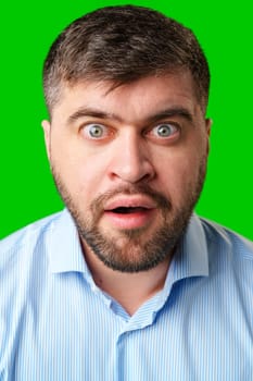 Surprised man with wide eyes and an open mouth against a bright green background in studio