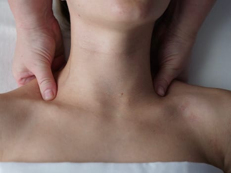 The masseur massages the client in the thoracic area of the collarbone. Close-up, no face