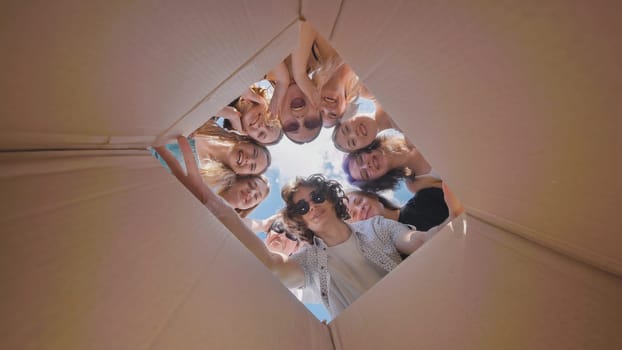 High school students happily exploring the contents of a cardboard box during the summer, filled with curiosity and excitement