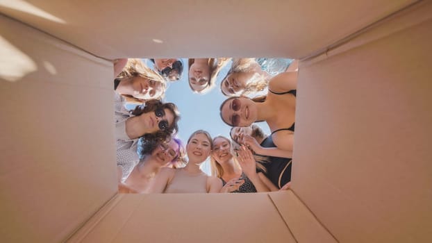 High school students peering into a cardboard box, enjoying a summer day full of curiosity and excitement