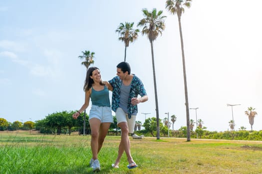 Happy friends walking laughing and holding each other in beautiful park with palm trees. High quality photo