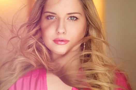 Woman with blue eyes and long, voluminous blonde hair styled in soft curls, wearing pink dress and elegant earrings, dreamy and feminine look idea