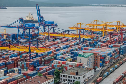 Cargo cranes loading multicolored shipping containers at vladivostok seaport, facilitating international maritime commerce in russia's far east
