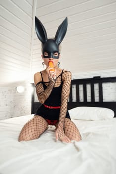 Sexy girl in a short black dress and a rabbit mask from a sex shop poses erotically in mesh bodysuit