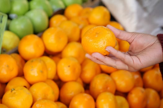 A hand picks a ripe orange from a colorful display of juicy citrus, showcasing natures bounty