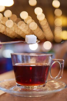 A picturesque closeup of tea being sweetened with sugar in a cozy, warm atmosphere