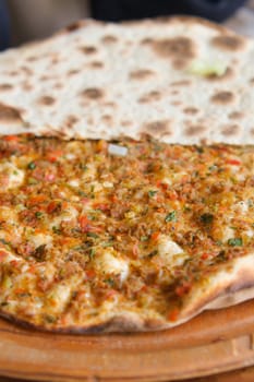 Savory pide, served piping hot and fresh, is topped with flavorful ingredients on a wooden platter