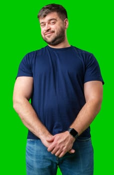 Man standing with a thoughtful expression in a casual outfit against a green background in studio