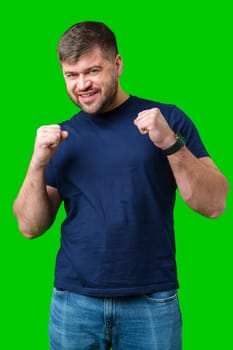 A strong man with fists raised, smiling confidently, on a bright green background in studio