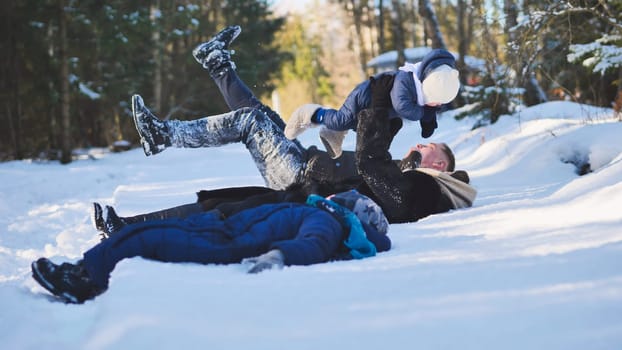 Happy family enjoying quality time together while playing in the snow with their baby, surrounded by serene trees in a winter forest