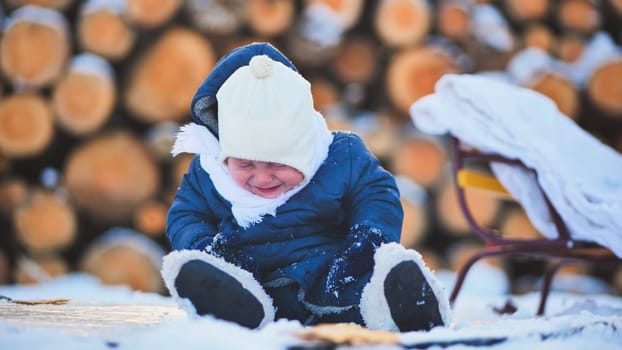 Distressed child weeping beside wooden sled, winter landscape with stacked firewood logs surrounding sad toddler