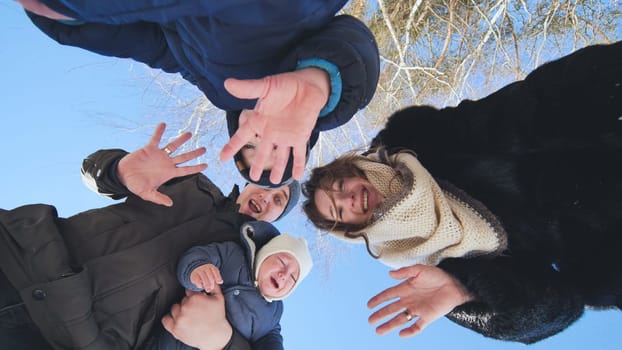 Happy family waving joyfully at the camera on a beautiful winter day, enjoying precious moments together outdoors in the snow