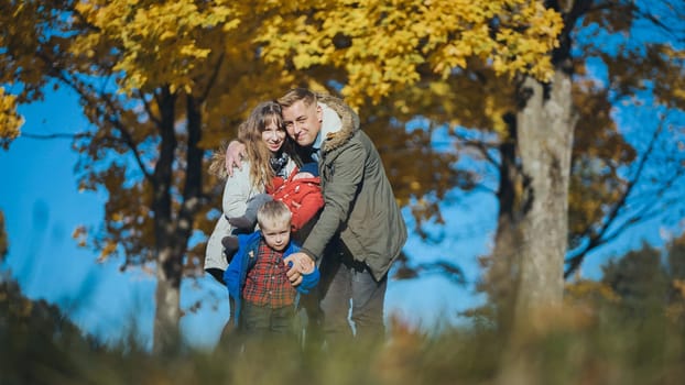 Family enjoying a beautiful autumn day in a park, surrounded by vibrant trees and colorful leaves, cherishing moments of joy and togetherness