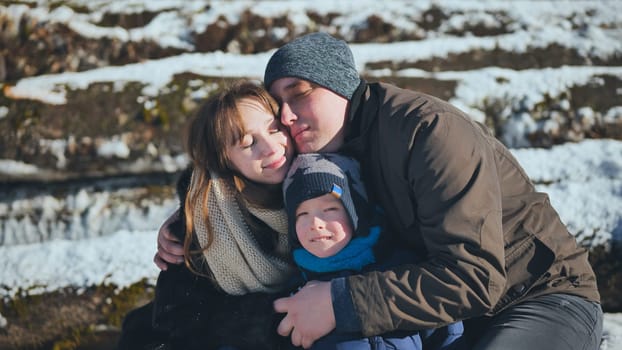 Smiling family sharing a warm embrace in a snowy winter landscape, creating cherished memories together in a joyful outdoor setting