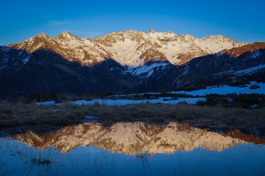 Sunset over the Pyrenees mountains with the reflection of the peaks in the water of the lake High quality 4k footage