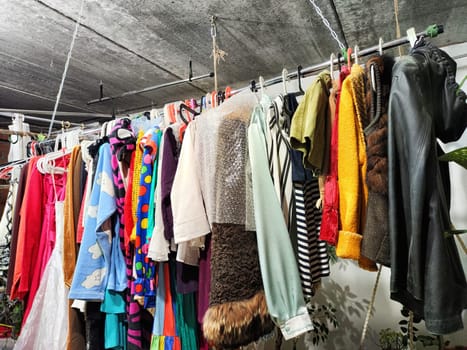 Colorful second-hand clothing is displayed at a garage sale, promoting sustainability and reducing waste in the community.