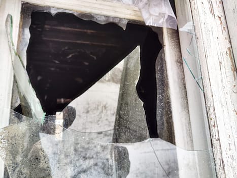 Shattered glass fragments surround an empty space indicating neglect in an abandoned building. Light filters through uneven edges.