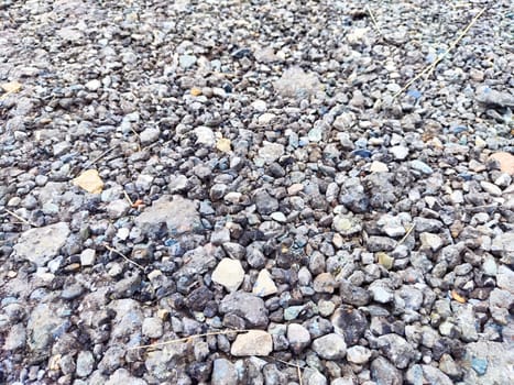 The surface features a rich variety of gravel stones in earth tones, providing an organic backdrop for text and design projects.