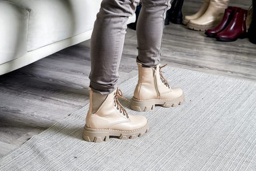 Model poses confidently in trendy shoes, highlighting the latest fashion style in a cozy indoor environment.