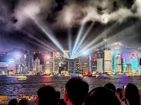 Hong Kong - April 05, 2024: Visitors gather at Victoria Bay to enjoy a stunning evening light show illuminating the iconic skyline of Hong Kong. Vibrant colors dance across impressive skyscrapers.
