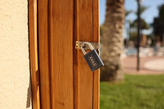 A strong padlock secures a crafted wooden door, amid lush greenery and swaying palms, ensuring safety for all