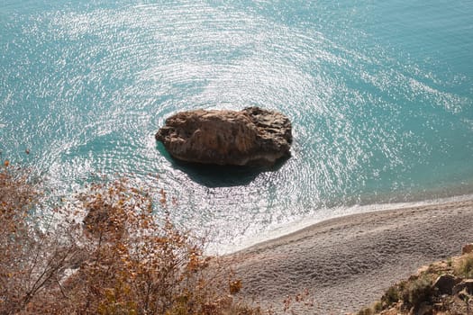 A tranquil view of a solitary rock in calm waters, showcasing the beauty of natures exquisite coastline
