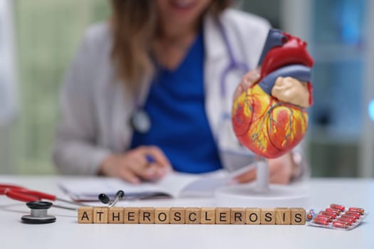 A dedicated healthcare professional diligently studying atherosclerosis using a heart model and various medical tools
