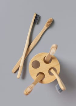 Beige bamboo toothbrushes in a holder cup on a light gray top view, copy space. Zero waste and no plastic concept.
Natural personal accessories for tooth care, minimal style