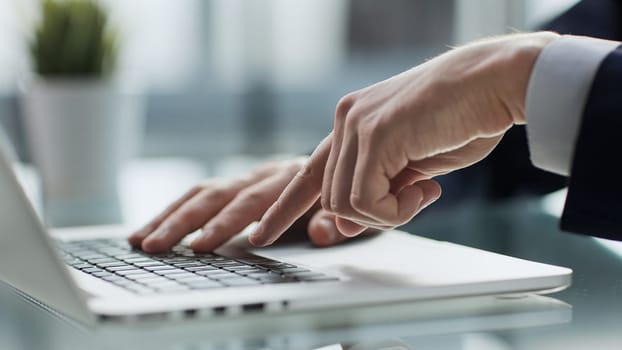 Closeup image of a man working and typing on laptop computer keyboard