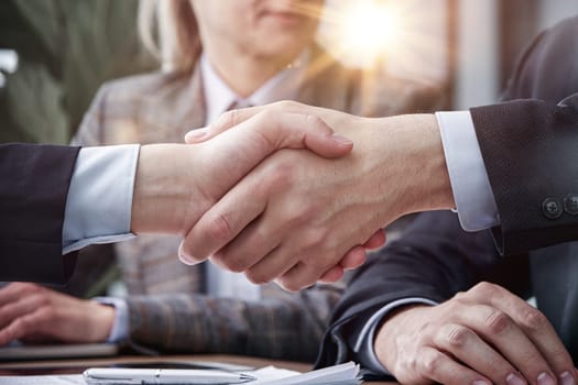 Two business people shaking hands in front of their colleagues