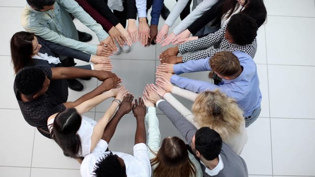 Team building and togetherness. Business people stretched out their hands towards each other while standing in a modern office.