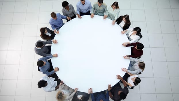 Top view of group of multiethnic busy people working in office, aerial view of sitting at negotiating table