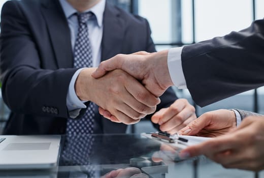 Businesspeople or lawyers shaking hands finishing up meeting or negotiation in sunny office. Business handshake and partnership