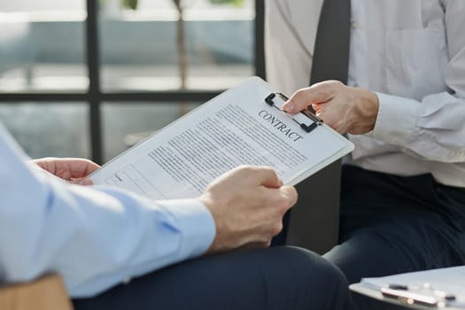 Close-up of businessmen looking at contract close-up while sitting in office