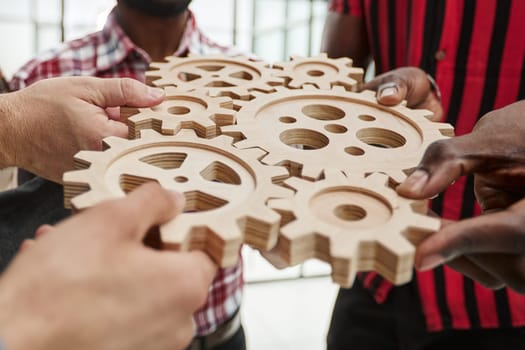 Office worker holding cog wheel as unity and teamwork in corporate workplace concept.