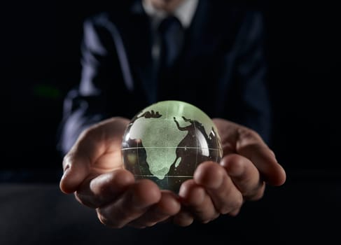 A man holds a glowing globe in his hands. close-up on a black background