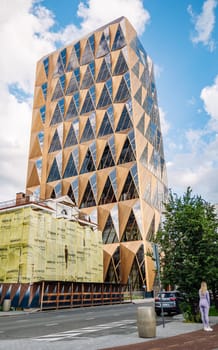 Modern geometric skyscraper with triangular glass and wood facade rises above a city street in yekaterinburg, russia, showcasing innovative architecture