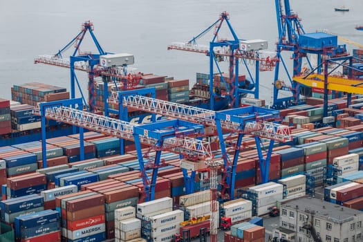 Industrial cargo cranes lifting multicolored shipping containers at busy russian maritime terminal, highlighting international commerce