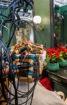 a young girl is getting her hair curled with curlers. the client is sitting in a chair with a lot of curlers on her head. hardware treatment and hair curling are being performed. close-up, rear view