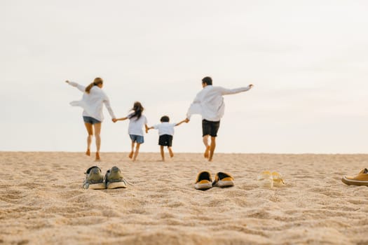 Happy family day. lifestyle father, mother and kids take off shoes running on sand, Back view Asian having family parents with child fun holding hands together run to beach, tropical summer vacations